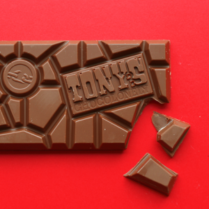Tony's Chocolonely bar on a red background with a piece broken off