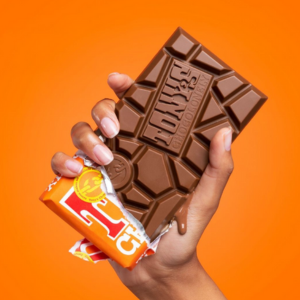 Tony's Chocolonely bar being held up with chocolate melting from it